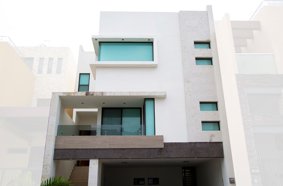 Photo of a large and white modern concrete house exterior in Other with three floors and a flat roof.