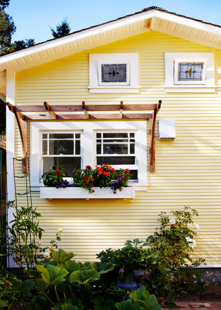 Esempio della facciata di una casa piccola gialla stile marinaro a un piano con rivestimento in legno e tetto a capanna
