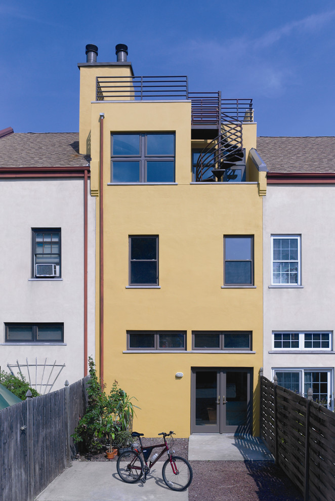 Imagen de fachada amarilla actual de tamaño medio de tres plantas con revestimiento de hormigón y tejado plano