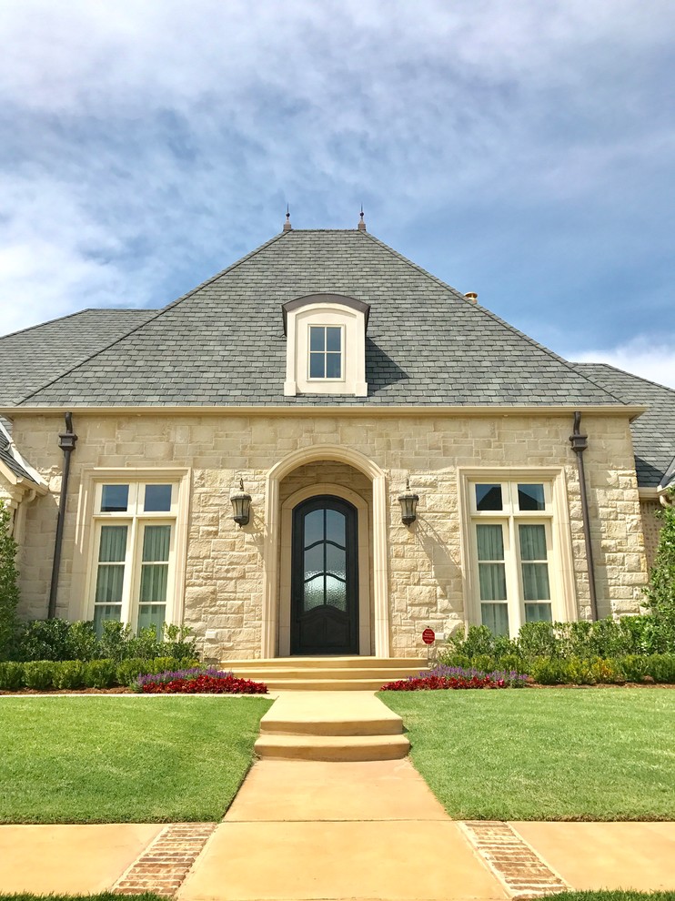 Mid-sized elegant beige stone house exterior photo in Oklahoma City with a hip roof and a shingle roof