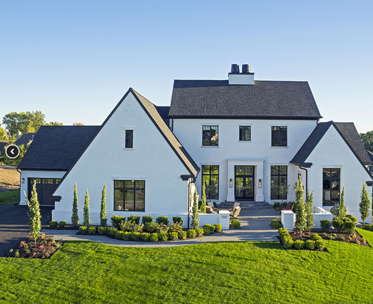 Large country white two-story stucco exterior home photo in Minneapolis with a shingle roof