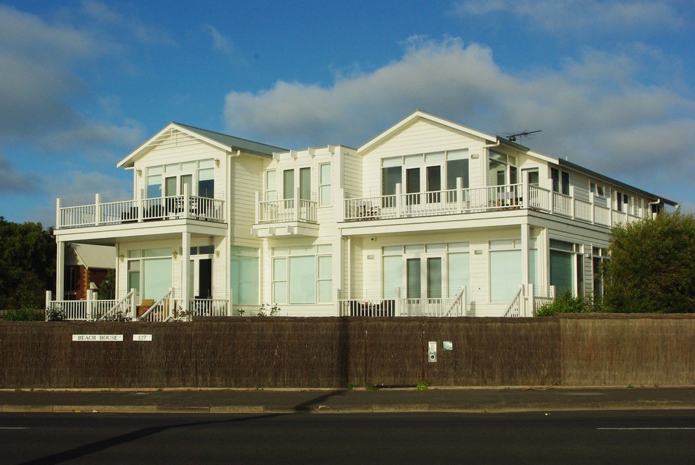 Esempio della facciata di una casa grande bianca classica a due piani con rivestimento in legno