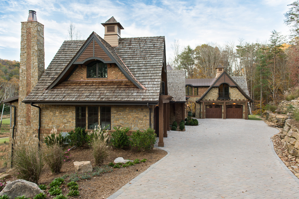 На фото: большой, двухэтажный, коричневый дом в классическом стиле с облицовкой из камня и двускатной крышей