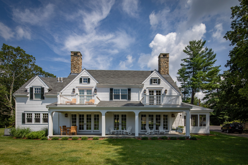 Foto della villa grande bianca country a due piani con rivestimento in legno, tetto a capanna e copertura a scandole