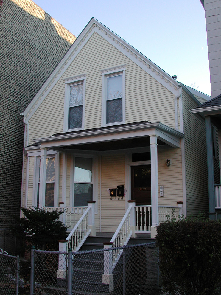 Mittelgroßes, Zweistöckiges Landhaus Haus mit Vinylfassade, gelber Fassadenfarbe und Flachdach in Chicago