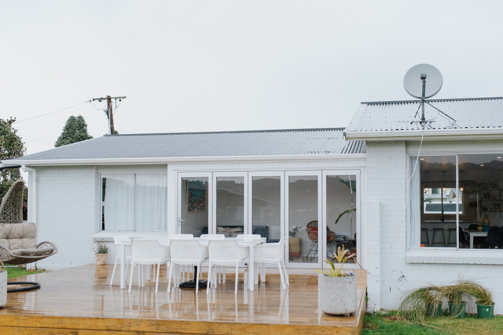 Foto de fachada de casa blanca costera grande de una planta con ladrillo pintado, tejado a dos aguas y tejado de metal