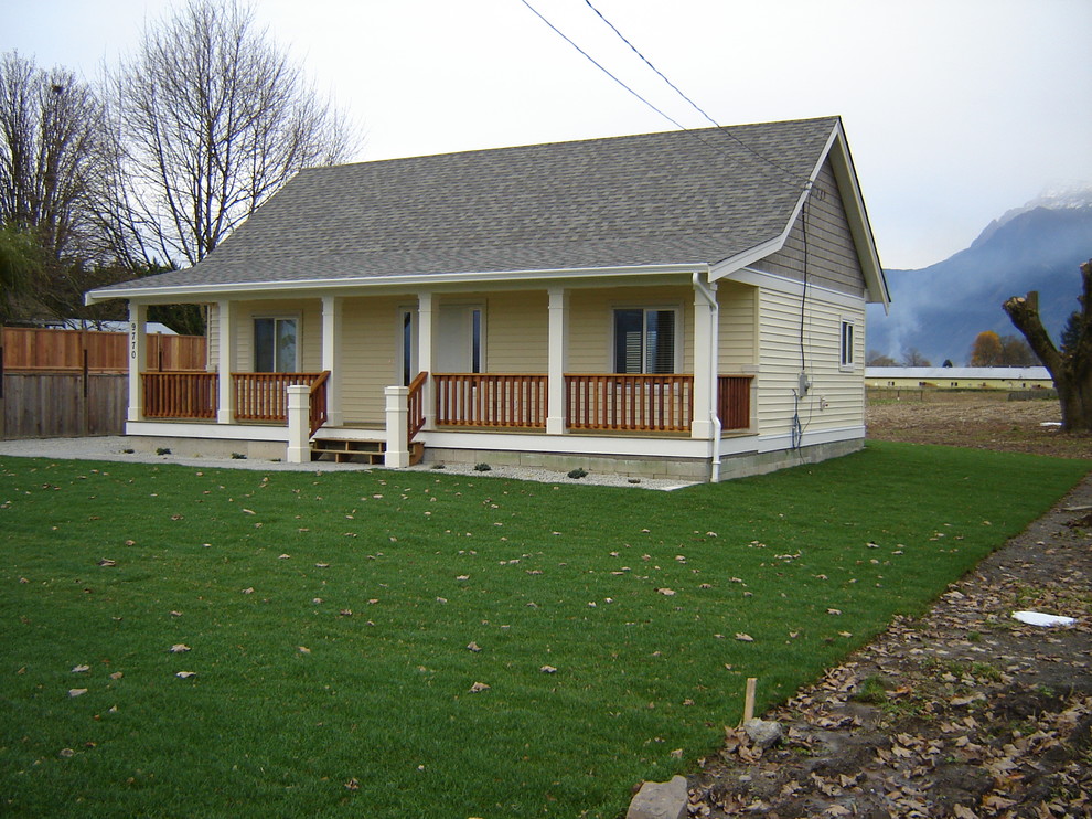 Small and yellow country bungalow detached house in Vancouver with vinyl cladding, a pitched roof and a shingle roof.