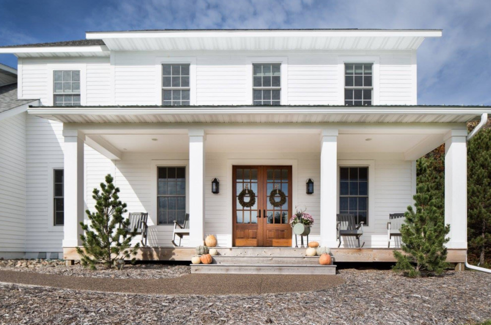 На фото: большой, двухэтажный, белый дом в стиле кантри с облицовкой из винила и односкатной крышей