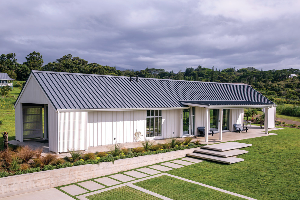 Esempio della villa bianca country a un piano con tetto a capanna e copertura in metallo o lamiera