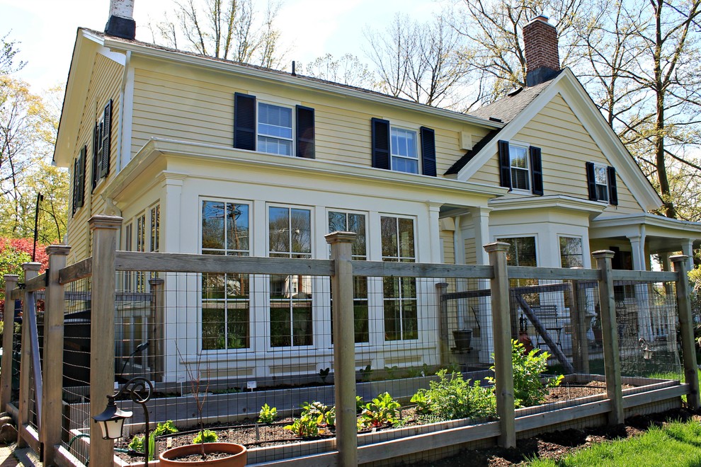 Réalisation d'une façade de maison jaune champêtre en bois de taille moyenne et à un étage.