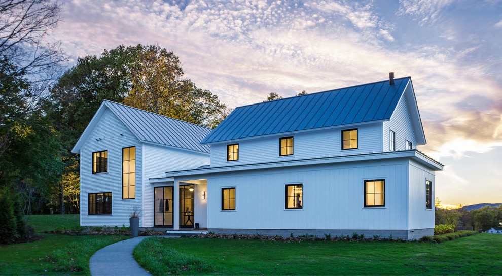 Imagen de fachada de casa blanca campestre de dos plantas con revestimiento de madera, tejado a dos aguas y tejado de metal