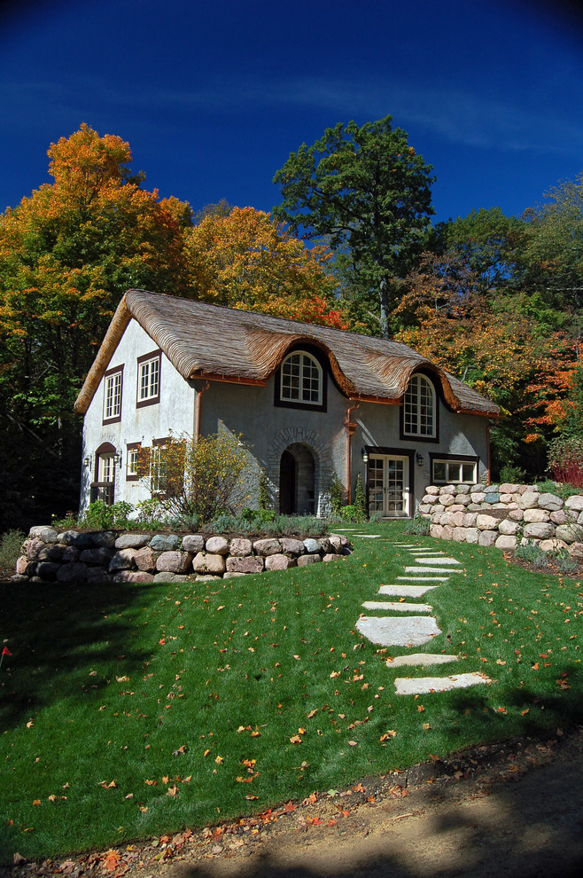 Ejemplo de fachada beige de estilo de casa de campo con revestimiento de estuco y tejado a dos aguas