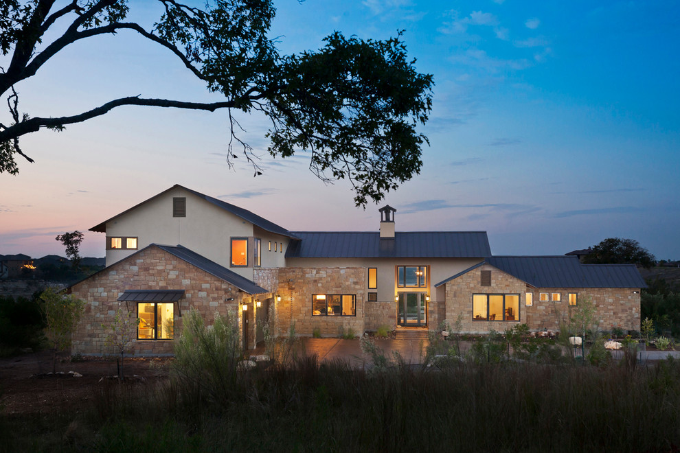 Zweistöckiges Landhaus Haus mit Steinfassade, beiger Fassadenfarbe und Satteldach in Austin
