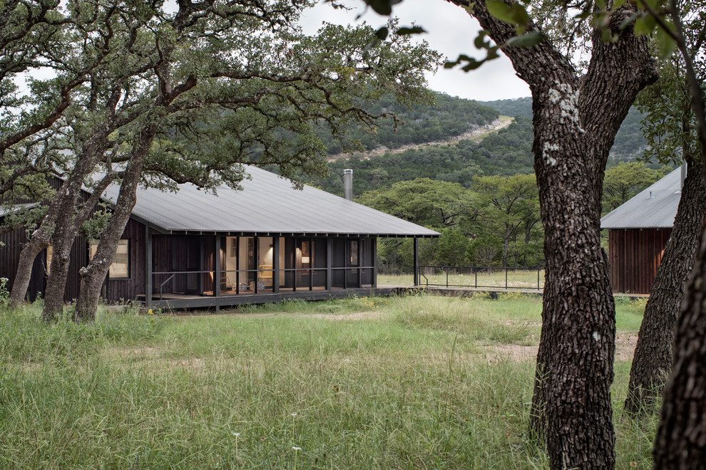 Photo of a small and black rural two floor detached house in Austin with wood cladding, a lean-to roof and a metal roof.