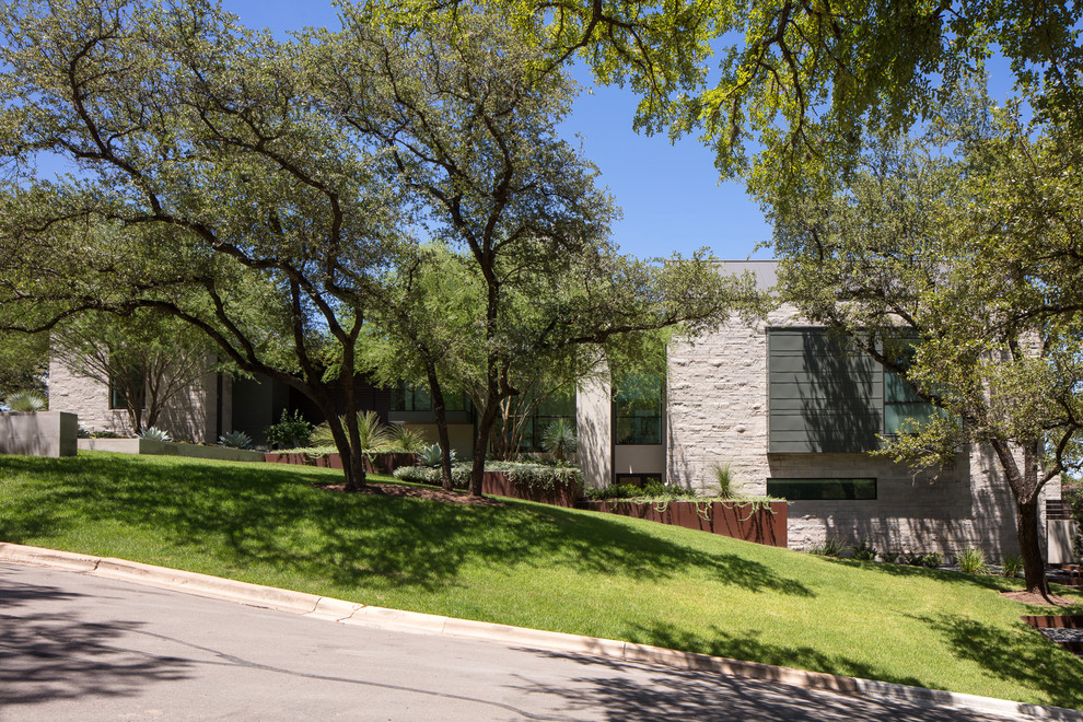 Large contemporary white two-story stone house exterior idea in Austin with a metal roof