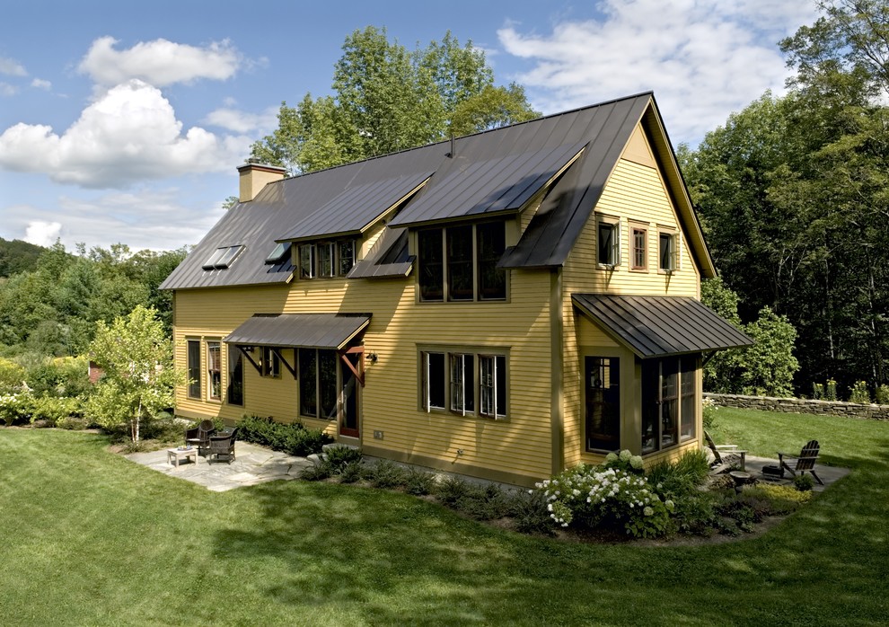 Foto della facciata di una casa country con rivestimento in legno e copertura in metallo o lamiera