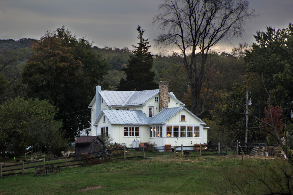 Foto della villa grande bianca country a due piani con tetto a capanna e copertura in metallo o lamiera