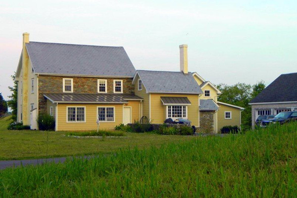 Foto della facciata di una casa gialla country a tre piani di medie dimensioni con rivestimenti misti e tetto a capanna