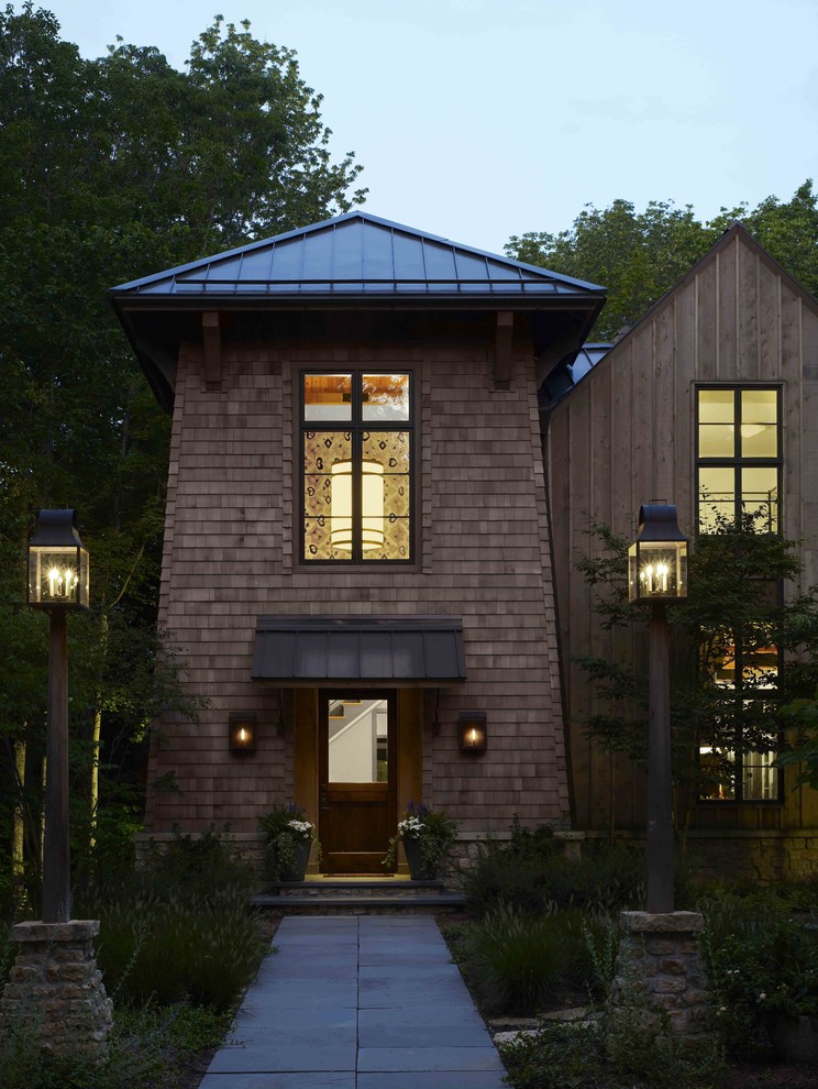 Immagine della facciata di una casa grande marrone country a due piani con rivestimento in legno