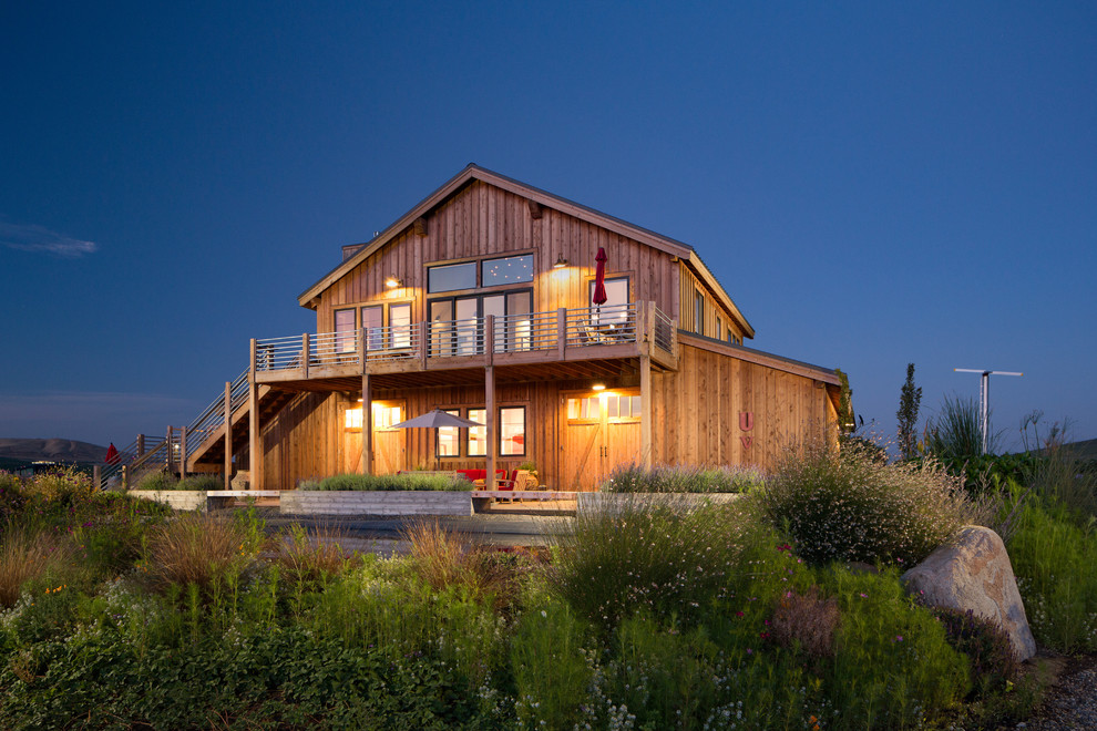Aménagement d'une grande façade de maison campagne en bois à un étage avec un toit à deux pans.