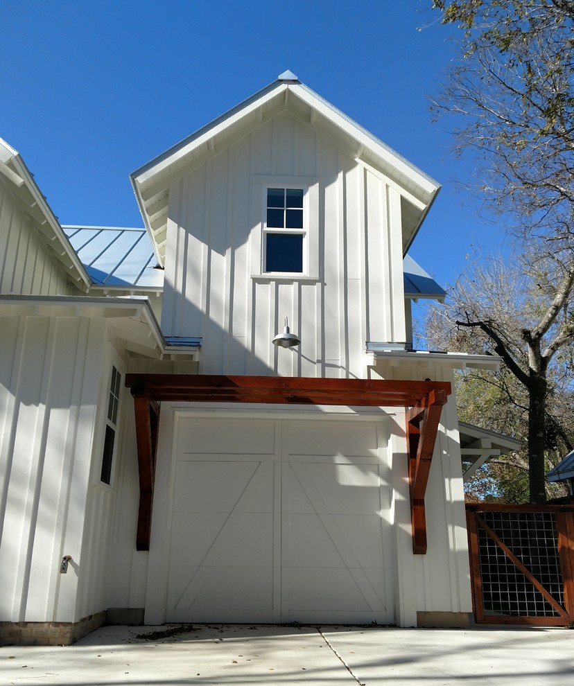 Esempio della villa piccola bianca country a due piani con rivestimento con lastre in cemento, tetto a capanna e copertura in metallo o lamiera
