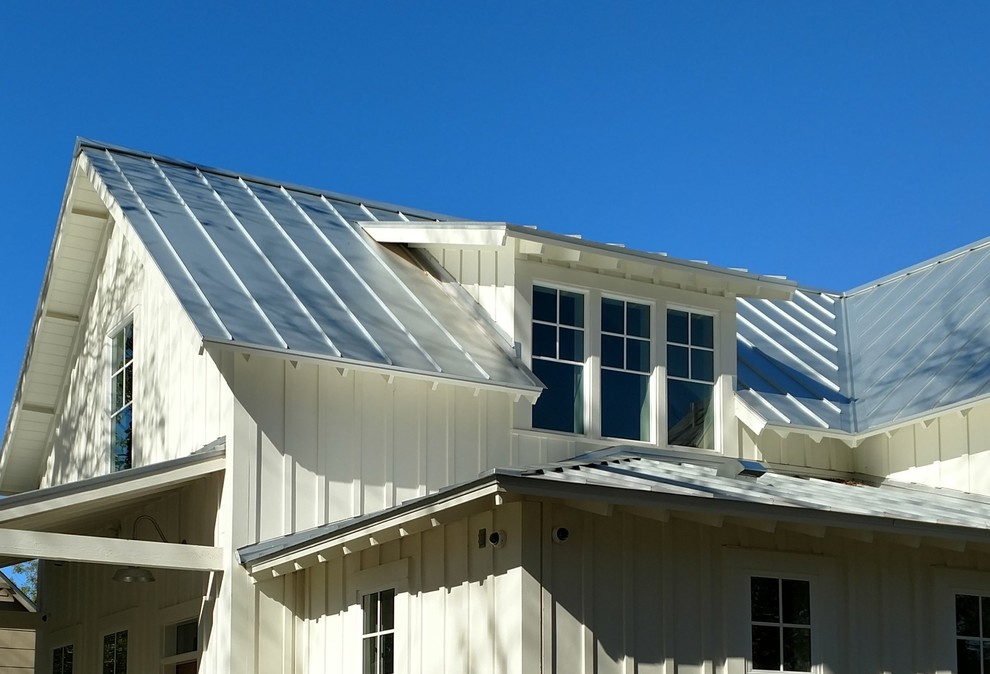 Imagen de fachada de casa blanca de estilo de casa de campo pequeña de dos plantas con revestimiento de aglomerado de cemento, tejado a dos aguas y tejado de metal