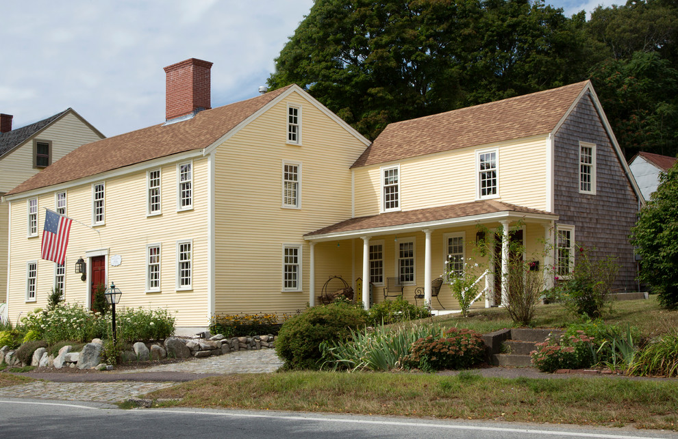 Cette image montre une grande façade de maison jaune traditionnelle en bois à un étage.
