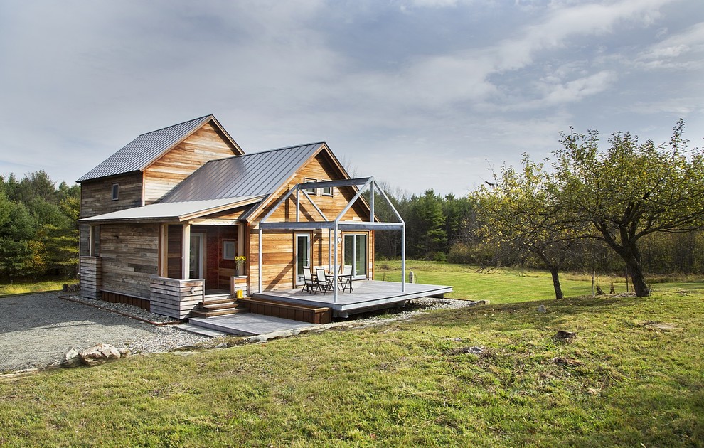 Immagine della facciata di una casa country a due piani con rivestimento in legno e tetto a capanna