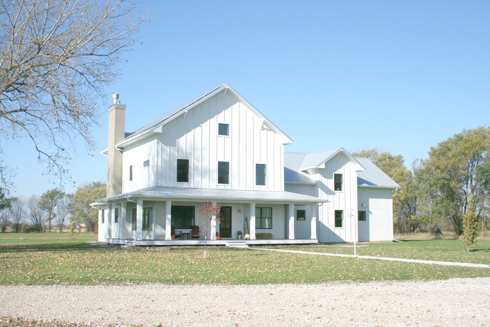 Foto della villa grande bianca country a tre piani con rivestimento in legno, tetto a capanna e copertura in metallo o lamiera