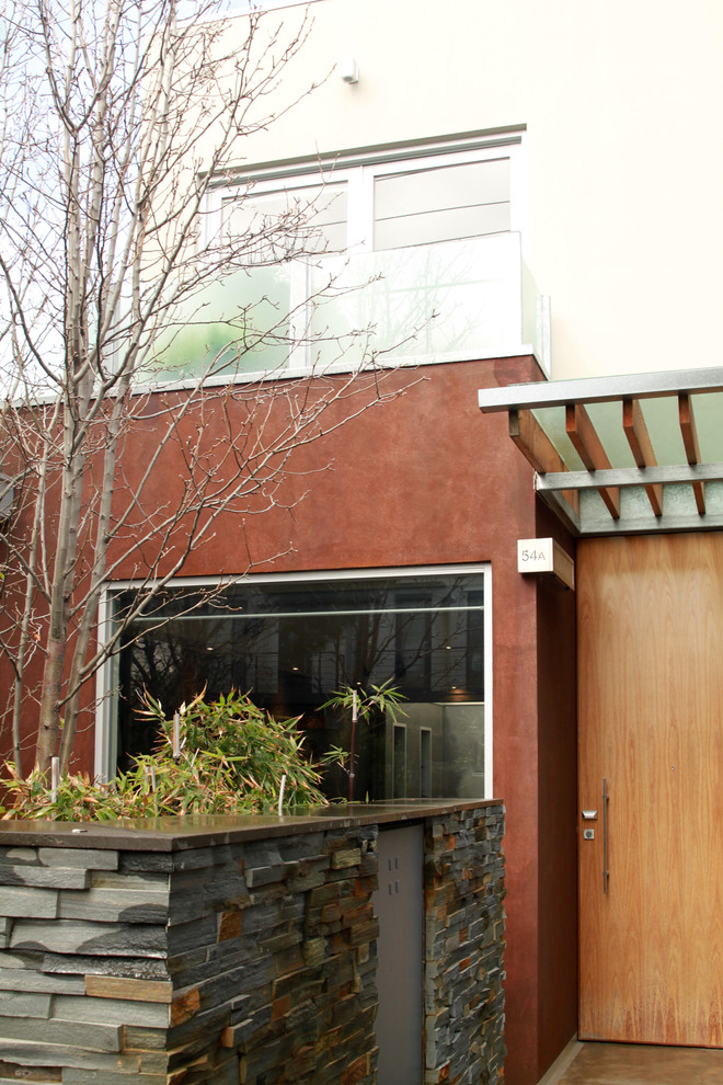 Idées déco pour une façade de maison marron éclectique en stuc à un étage.