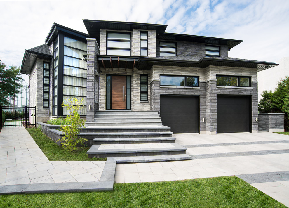 Diseño de fachada de casa gris actual grande de dos plantas con revestimientos combinados y tejado a dos aguas