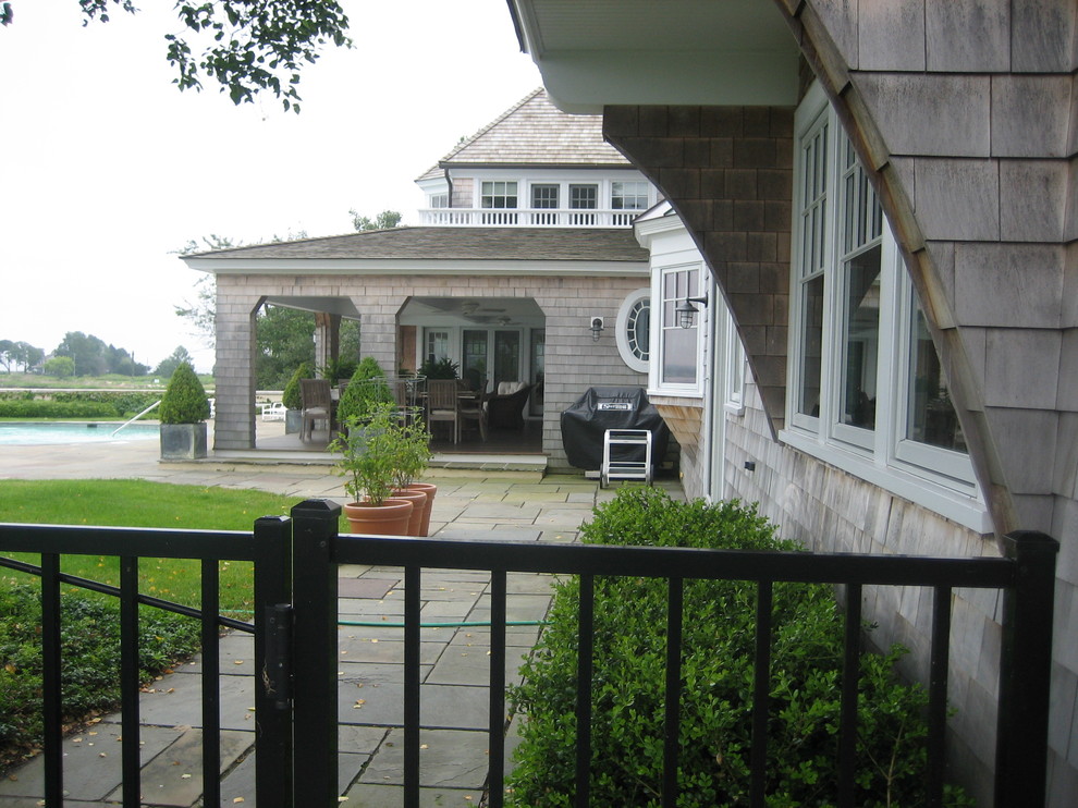 На фото: большой, трехэтажный, деревянный, серый частный загородный дом в морском стиле с вальмовой крышей и крышей из гибкой черепицы с