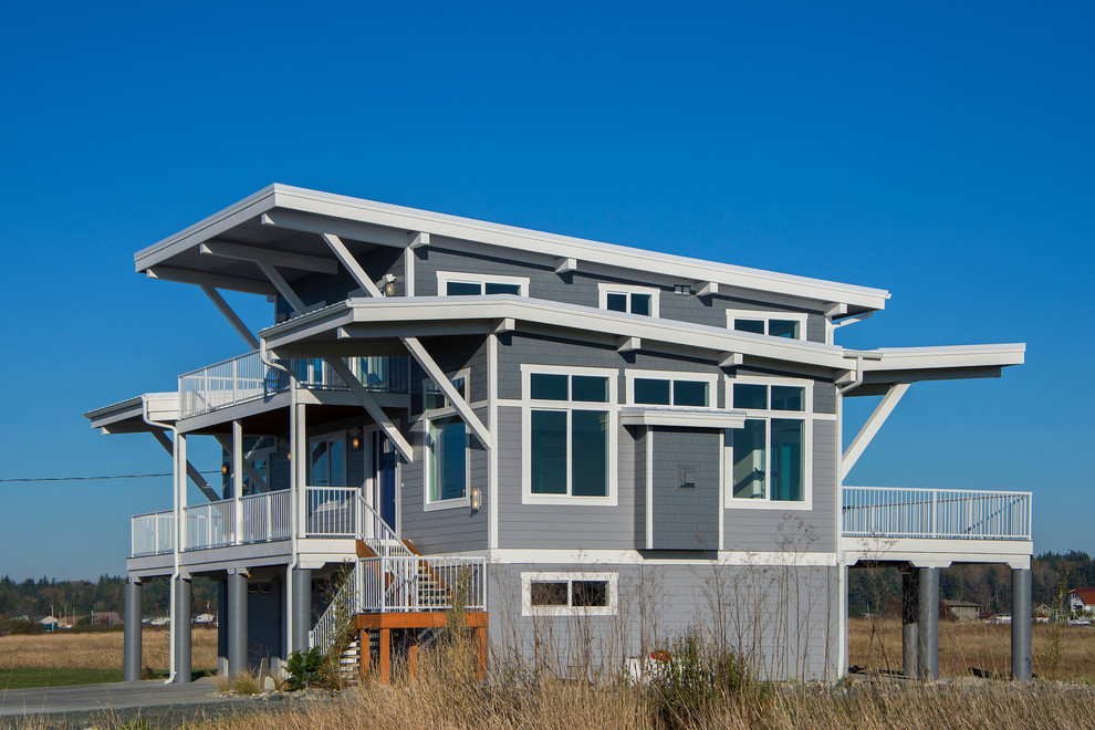 Exemple d'une grande façade de maison grise chic à deux étages et plus avec un revêtement en vinyle et un toit plat.