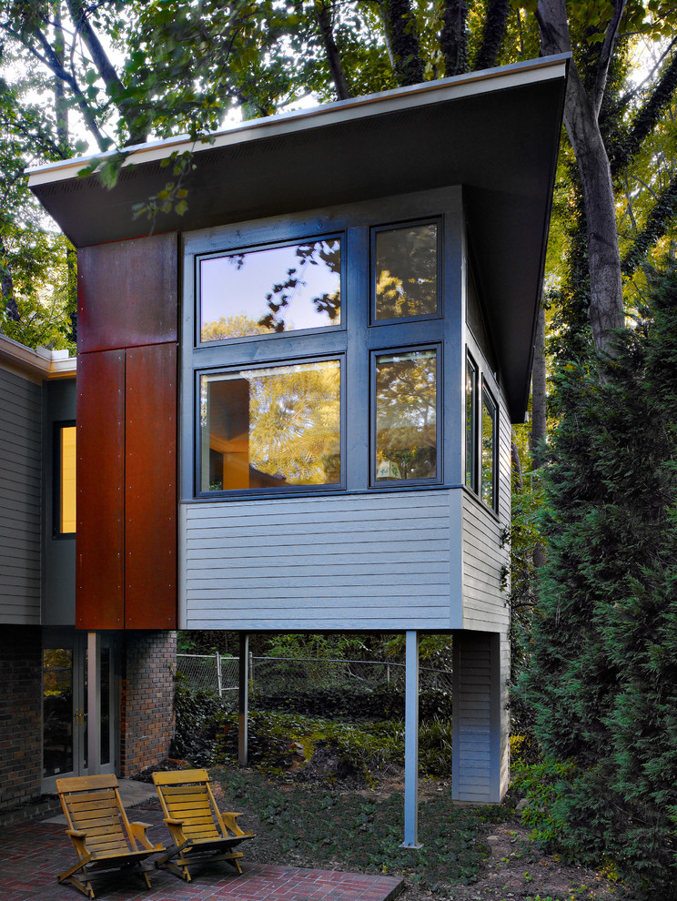 Пример оригинального дизайна: двухэтажный, серый частный загородный дом среднего размера в современном стиле с комбинированной облицовкой и односкатной крышей