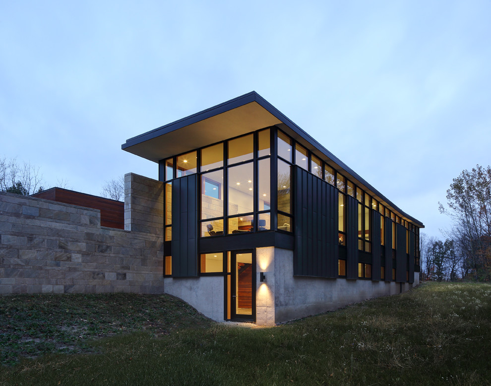 Aménagement d'une façade de maison noire moderne de taille moyenne et à un étage avec un revêtement mixte et un toit plat.