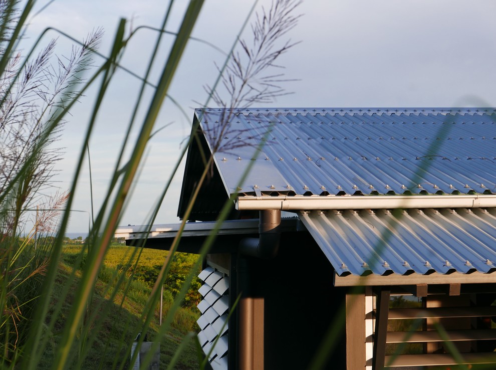 Exemple d'une petite façade de maison noire exotique en bois de plain-pied avec un toit à deux pans et un toit en métal.