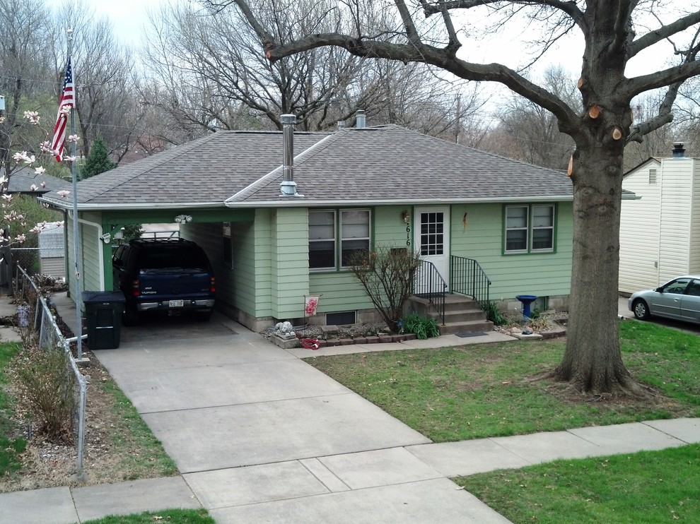 This is an example of a small and green classic bungalow house exterior in Omaha with vinyl cladding and a hip roof.