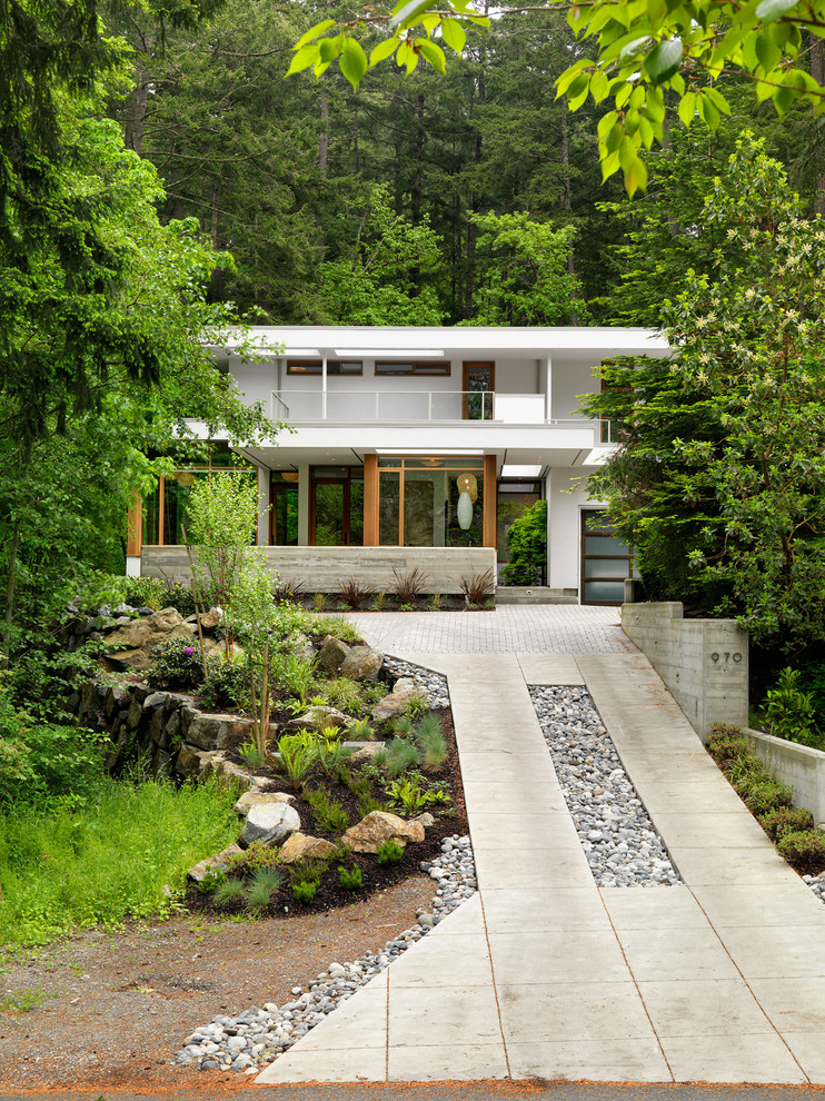 Diseño de fachada de casa blanca moderna de tamaño medio de una planta con revestimiento de estuco y tejado plano