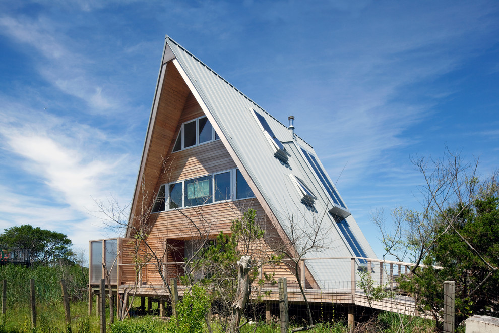 Foto della villa piccola marrone contemporanea a tre piani con rivestimento in legno, tetto a capanna e copertura in metallo o lamiera