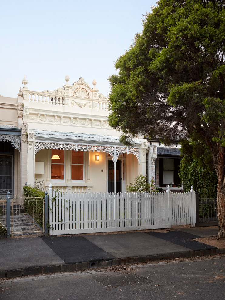 Kleines, Zweistöckiges Klassisches Reihenhaus mit Putzfassade, weißer Fassadenfarbe, Flachdach und Blechdach in Melbourne