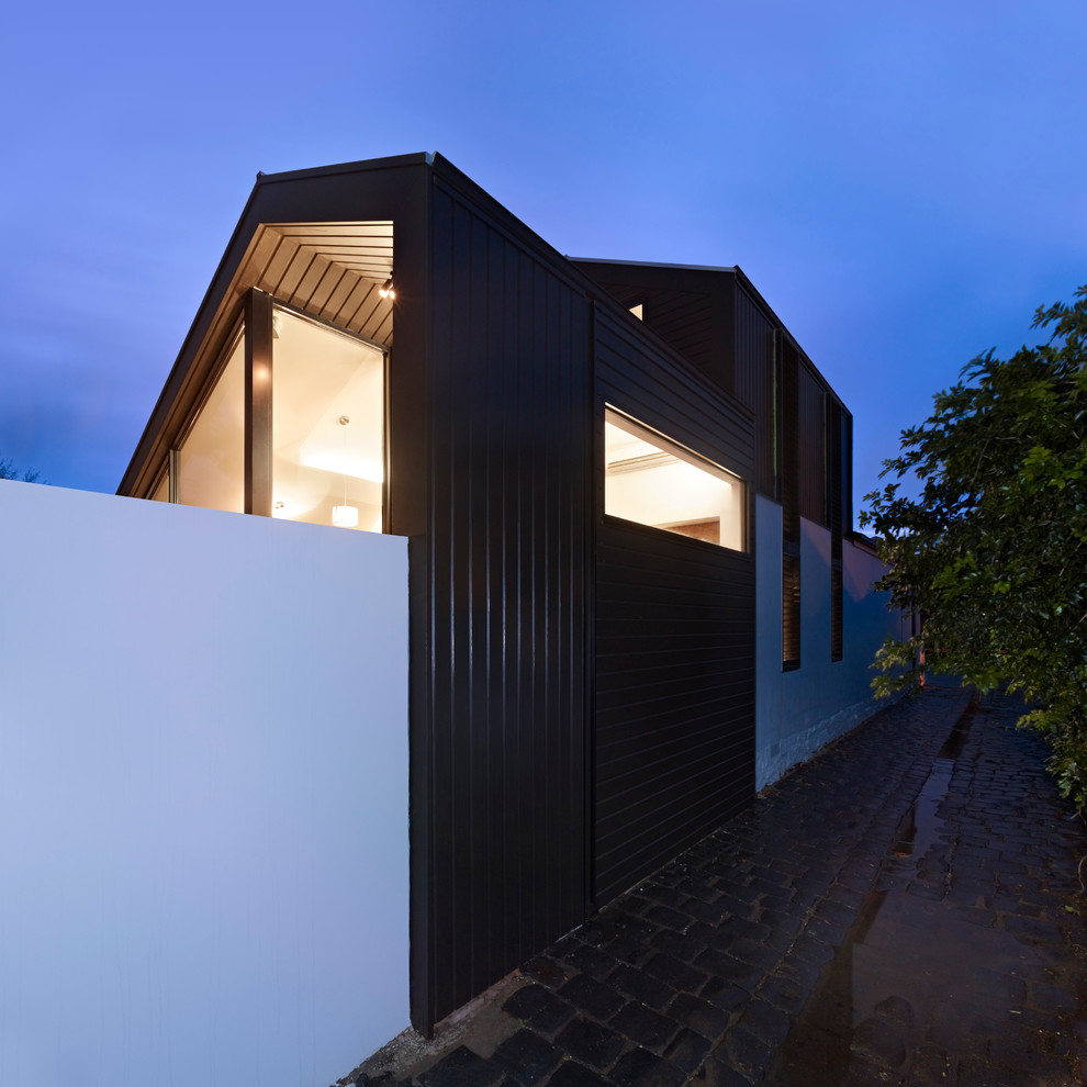 На фото: маленький, двухэтажный, деревянный, черный дом в стиле модернизм с двускатной крышей для на участке и в саду с