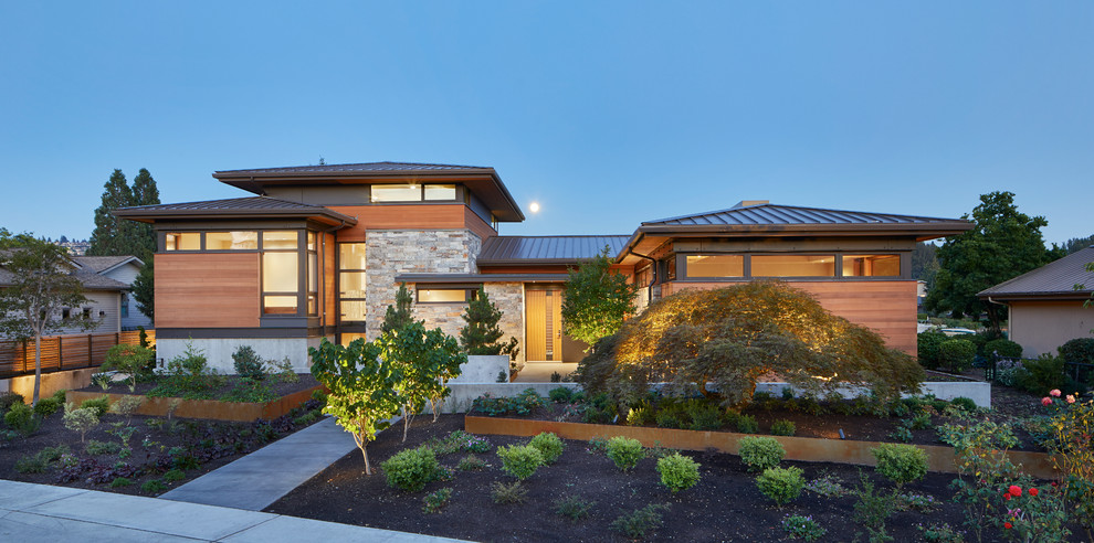 Modelo de fachada de casa marrón contemporánea a niveles con revestimientos combinados, tejado a cuatro aguas y tejado de metal