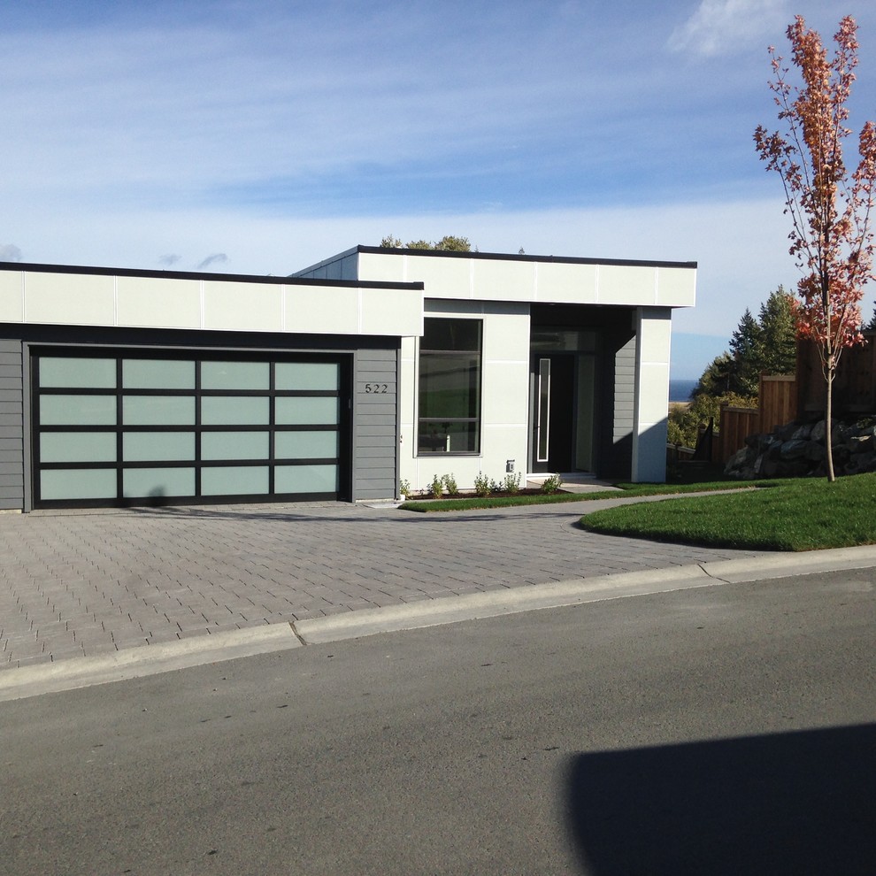 This is an example of a medium sized and gey contemporary bungalow concrete detached house in Vancouver with a flat roof.