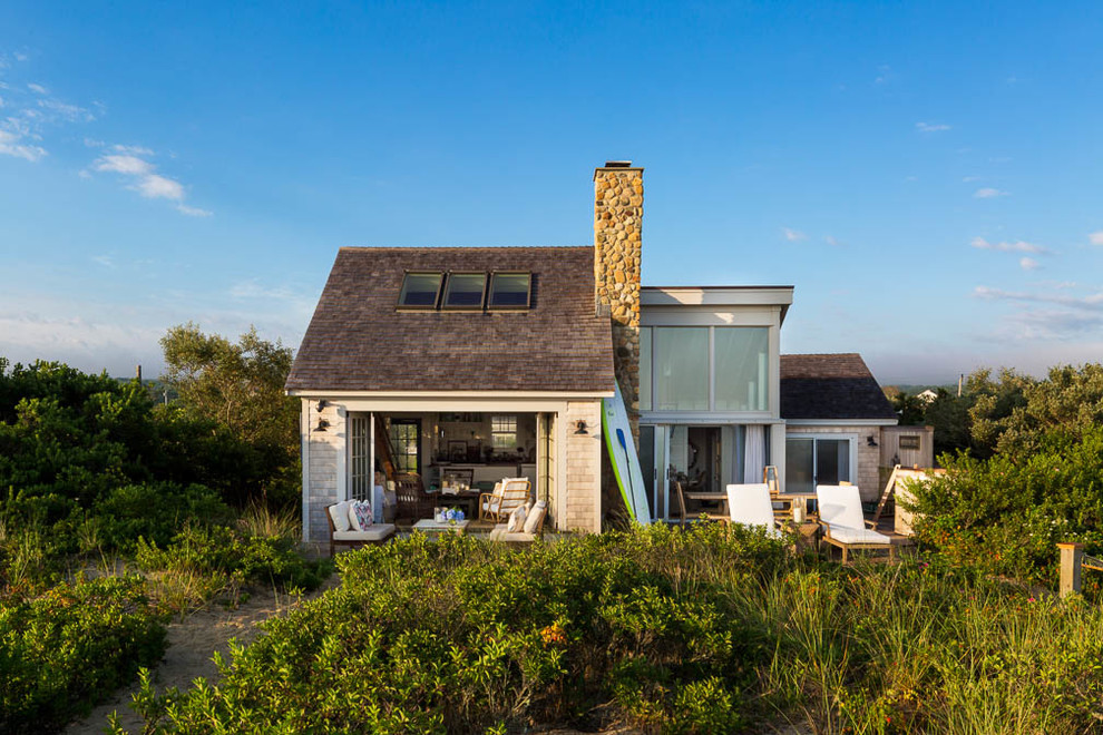 This is an example of a small beach style two floor house exterior in Boston with wood cladding and a lean-to roof.
