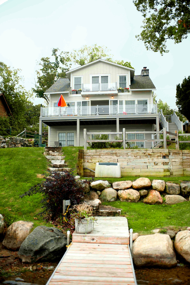 Cette photo montre une grande façade de maison beige bord de mer en panneau de béton fibré à deux étages et plus avec un toit à deux pans.