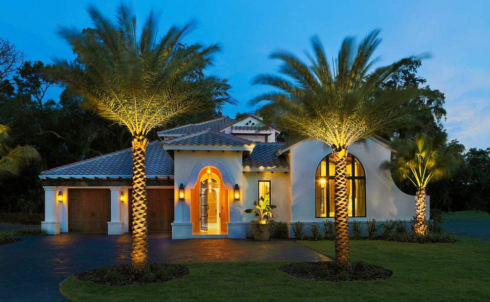 Inspiration for a mid-sized tropical beige two-story stucco house exterior remodel in Tampa with a hip roof and a tile roof