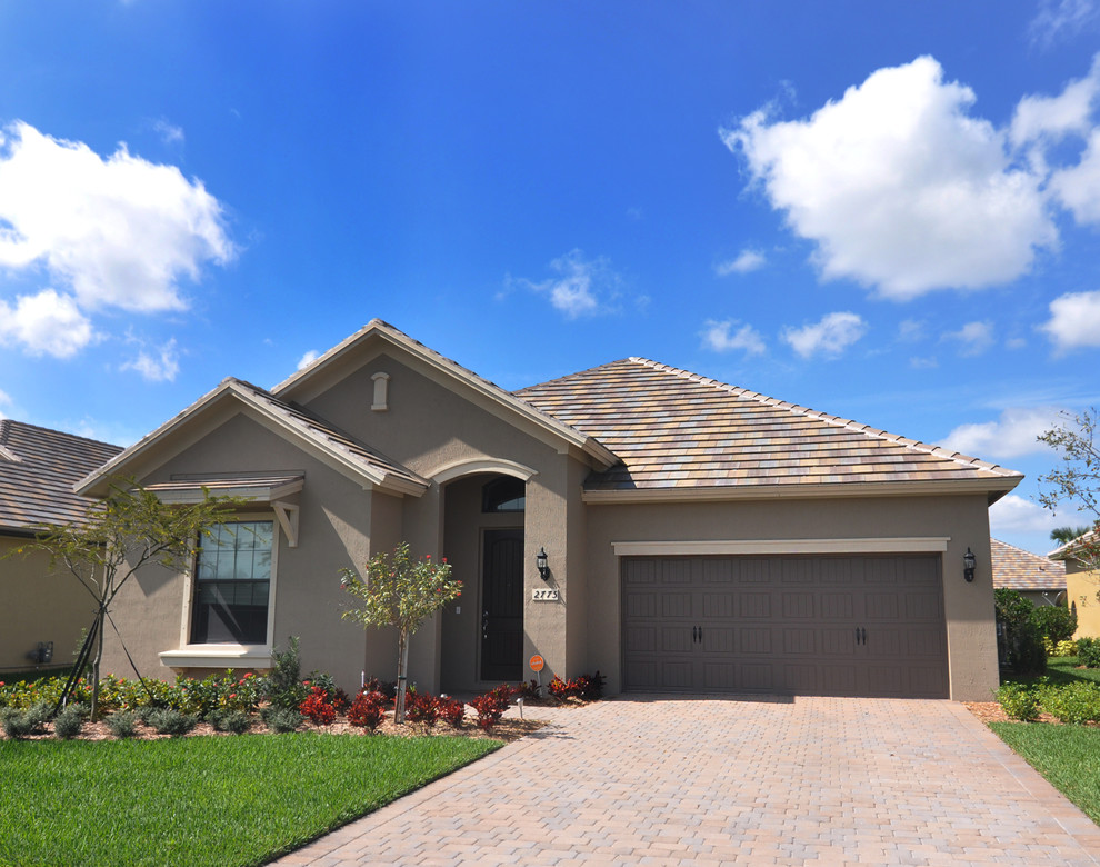 Medium sized and gey world-inspired bungalow render house exterior in Tampa with a pitched roof.