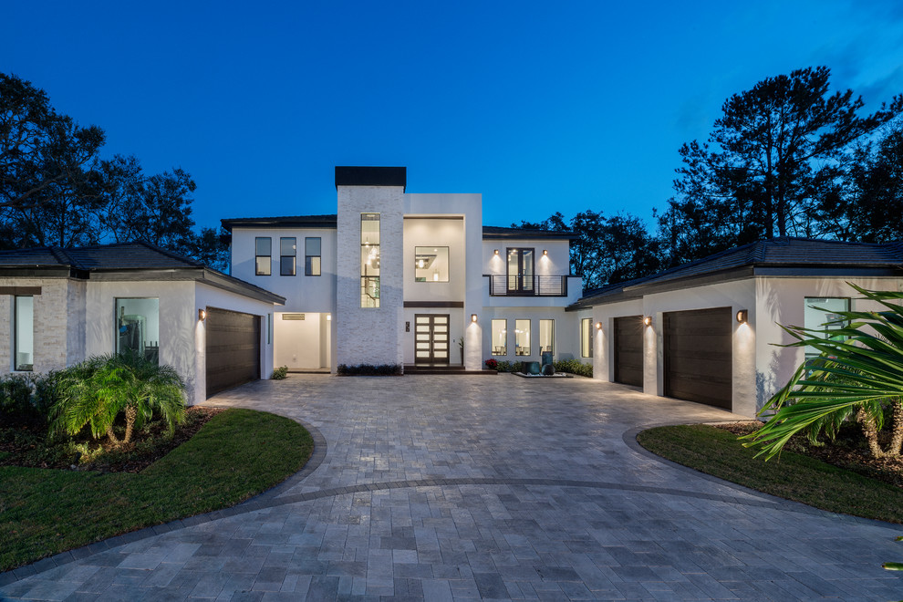 Example of a large trendy white two-story stucco exterior home design in Orlando with a tile roof
