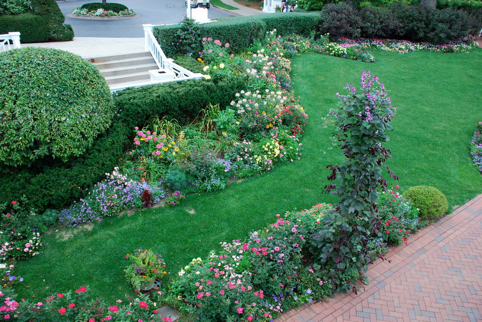На фото: большой летний регулярный сад на боковом дворе в классическом стиле с полуденной тенью и мощением клинкерной брусчаткой с
