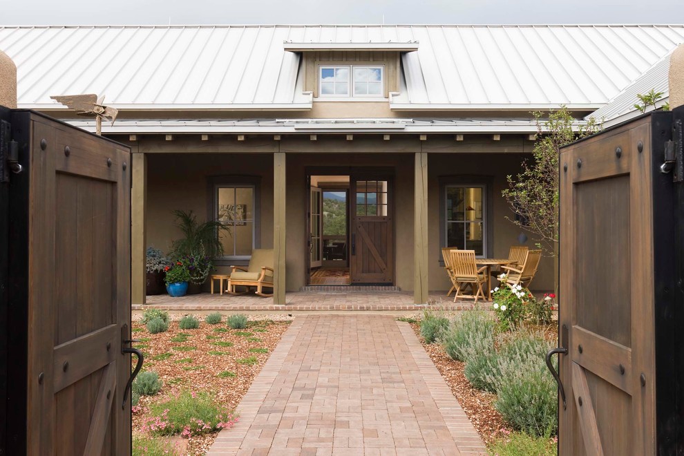 Mittelgroßes, Einstöckiges Country Einfamilienhaus mit Lehmfassade, beiger Fassadenfarbe, Satteldach, Blechdach und weißem Dach in Albuquerque